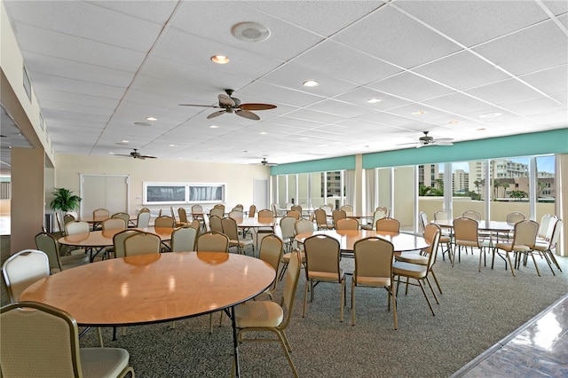 dining area with ceiling fan, a drop ceiling, and carpet flooring