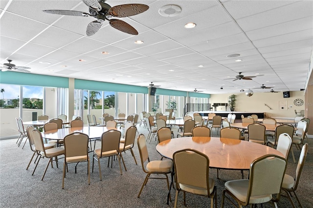 carpeted dining space with a drop ceiling