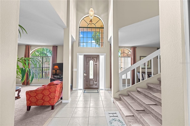 foyer with a high ceiling, a textured ceiling, and light tile patterned floors