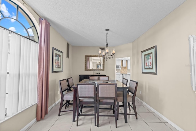 tiled dining room featuring a textured ceiling and a chandelier