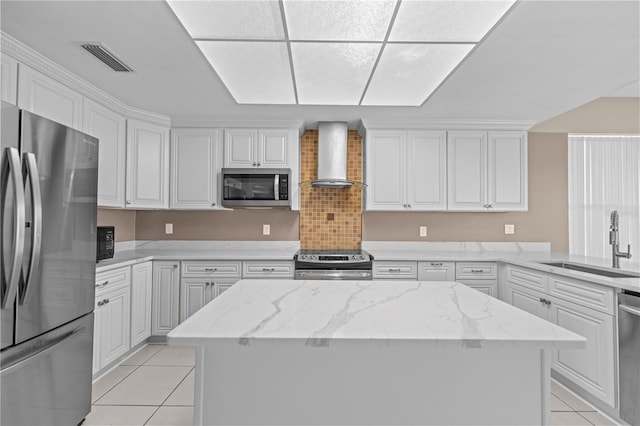 kitchen featuring wall chimney exhaust hood, stainless steel appliances, white cabinets, and a center island