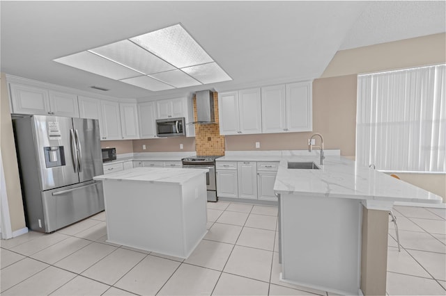 kitchen with wall chimney exhaust hood, white cabinets, appliances with stainless steel finishes, and sink