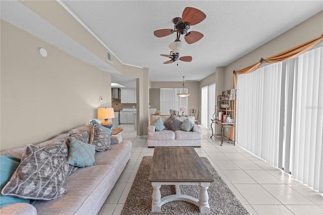 living room featuring ceiling fan, light tile patterned floors, and a textured ceiling