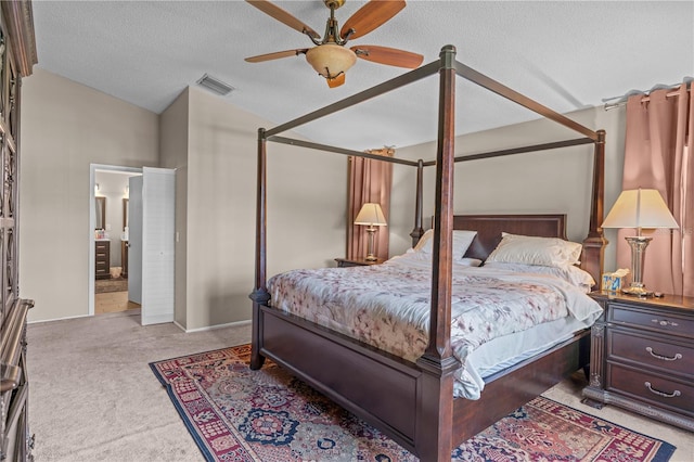 bedroom featuring a textured ceiling, lofted ceiling, light colored carpet, ensuite bath, and ceiling fan