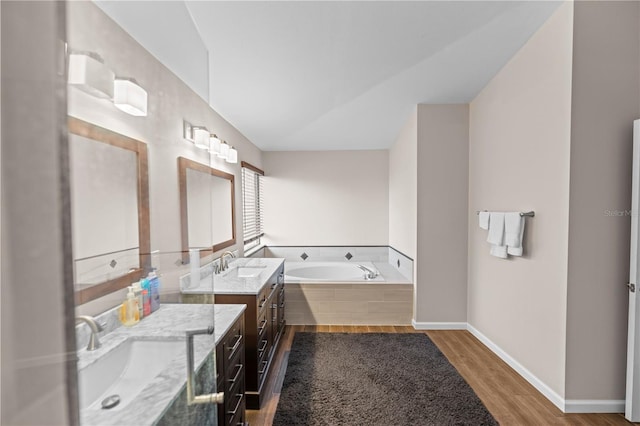 bathroom featuring tiled tub, vanity, and hardwood / wood-style flooring