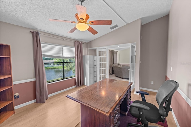 office area with ceiling fan, lofted ceiling, french doors, light hardwood / wood-style flooring, and a water view