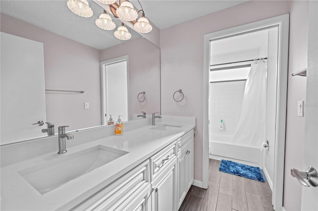 bathroom featuring a textured ceiling, wood-type flooring, shower / tub combo with curtain, and vanity