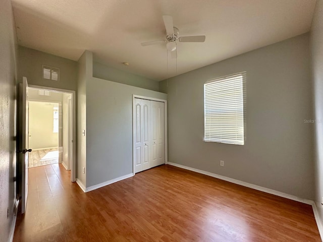 unfurnished bedroom with wood-type flooring, a closet, and ceiling fan