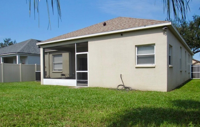 rear view of property featuring a sunroom and a yard