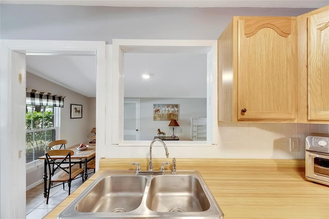 kitchen featuring light brown cabinets, sink, and tasteful backsplash