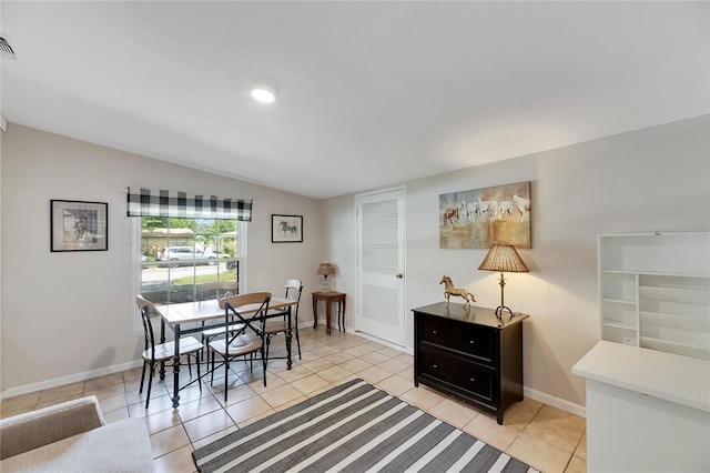 dining space with vaulted ceiling and light tile patterned flooring