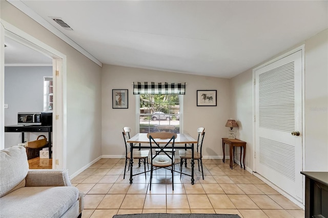 dining space with ornamental molding, light tile patterned flooring, and vaulted ceiling