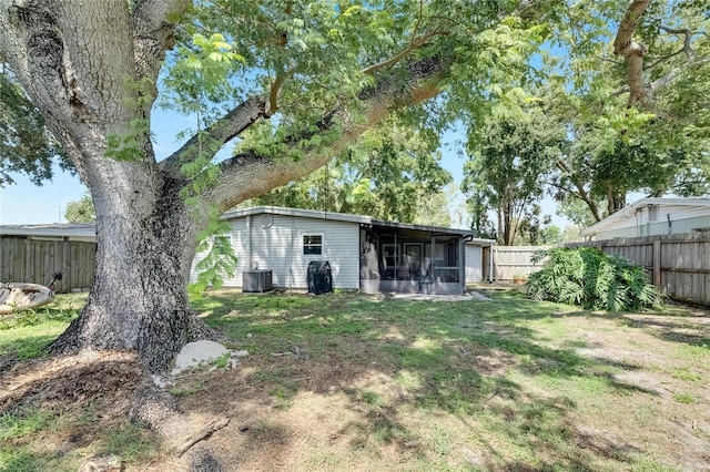 rear view of house with a sunroom, a lawn, and central air condition unit