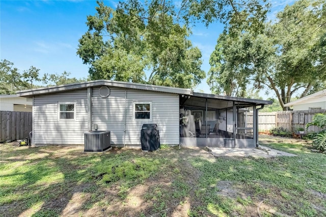 back of house featuring a sunroom, central AC, and a lawn