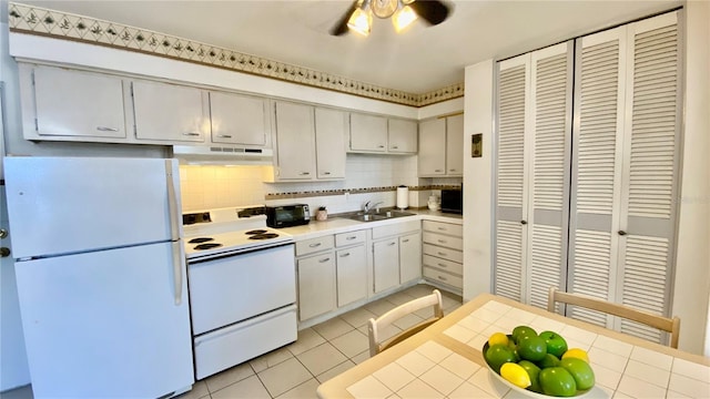 kitchen with white appliances, light tile patterned flooring, ceiling fan, and tile countertops