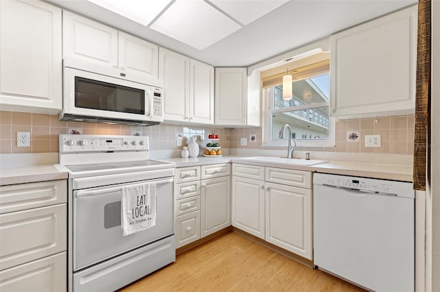 kitchen featuring white appliances, white cabinets, a sink, and light wood-style floors