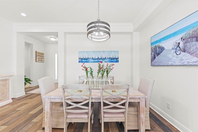 dining space featuring wood-type flooring, a notable chandelier, and crown molding