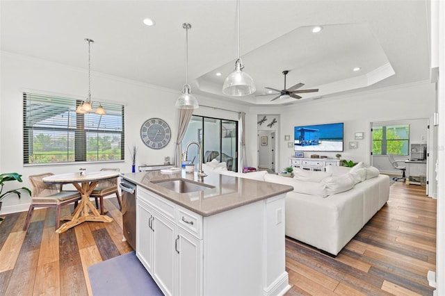 kitchen with decorative light fixtures, hardwood / wood-style flooring, a kitchen island with sink, and sink