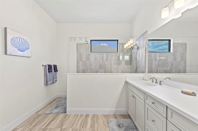 bathroom with vanity, a tile shower, hardwood / wood-style flooring, and a healthy amount of sunlight