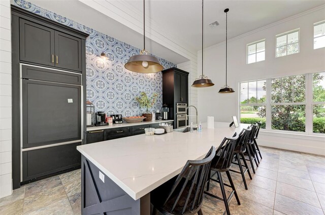 kitchen with a kitchen island with sink, pendant lighting, and plenty of natural light