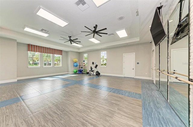 workout room featuring ceiling fan and a raised ceiling