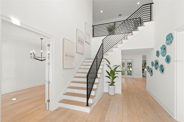 stairway featuring a notable chandelier, hardwood / wood-style floors, and a high ceiling