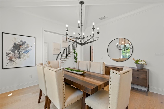 dining room featuring light hardwood / wood-style flooring, a chandelier, lofted ceiling with beams, and ornamental molding