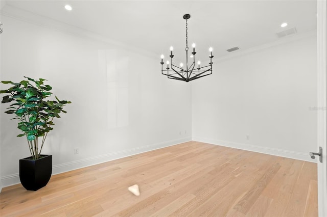 unfurnished room with a notable chandelier, light hardwood / wood-style flooring, and ornamental molding