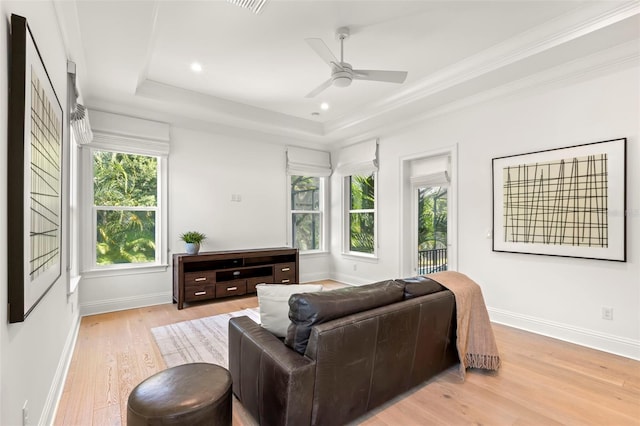 living room featuring light hardwood / wood-style flooring, a tray ceiling, ceiling fan, and ornamental molding