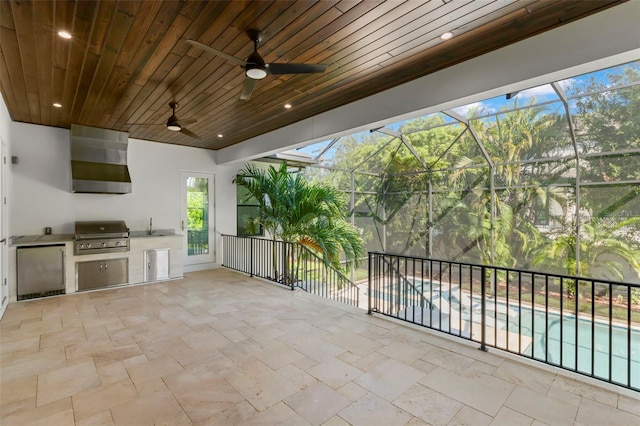 view of patio with a lanai, grilling area, ceiling fan, exterior kitchen, and sink