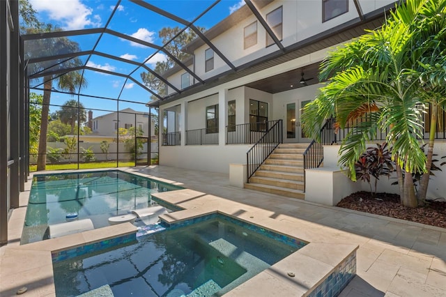 view of pool featuring glass enclosure, an in ground hot tub, ceiling fan, and a patio