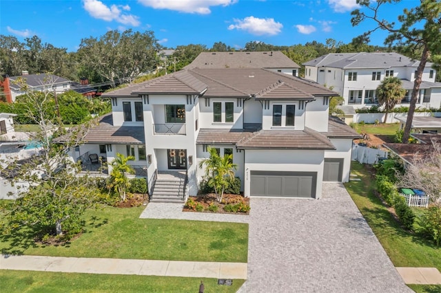 view of front of property featuring a balcony, a front lawn, and a garage