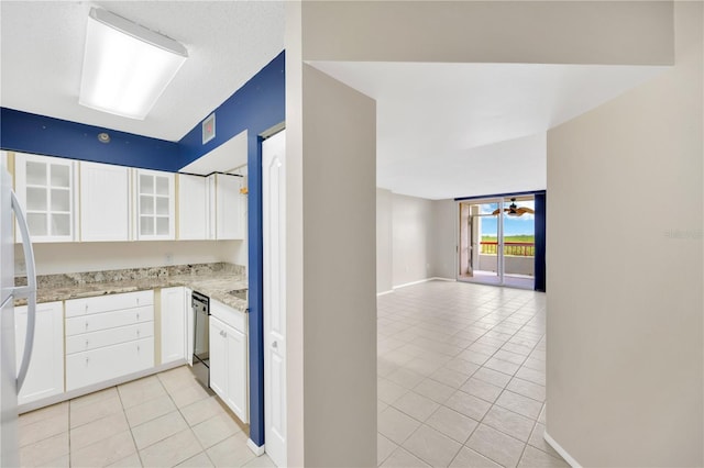 kitchen featuring light stone countertops, ceiling fan, black dishwasher, white cabinetry, and light tile patterned flooring