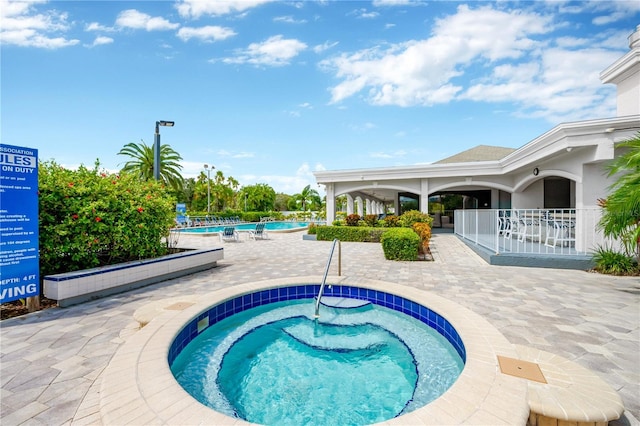 view of swimming pool with a patio area and a community hot tub