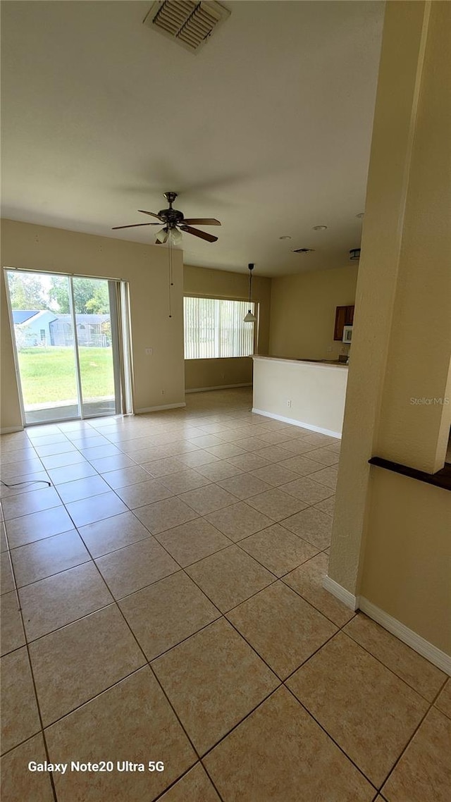 tiled empty room featuring ceiling fan and a wealth of natural light