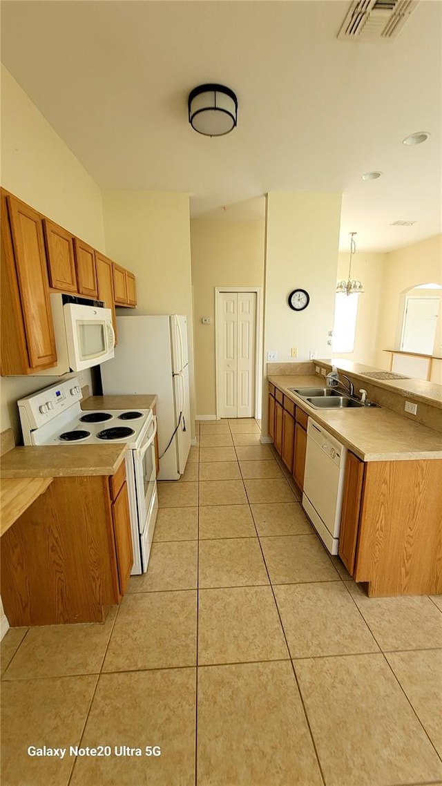 kitchen featuring pendant lighting, light tile patterned flooring, sink, and white appliances