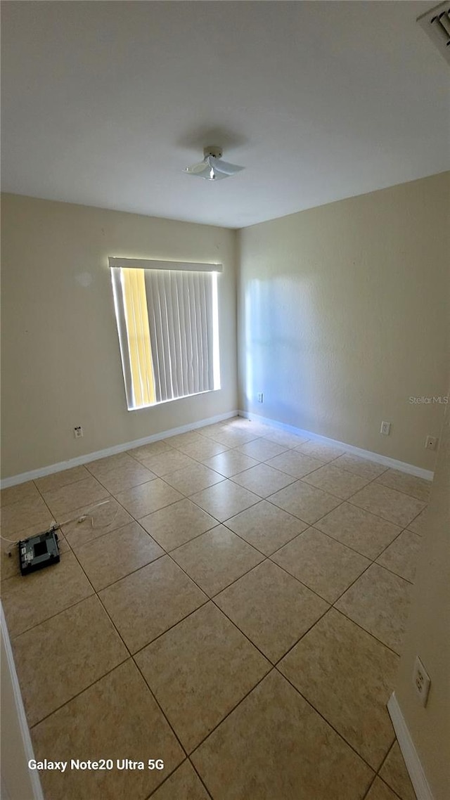 empty room with ceiling fan and light tile patterned floors