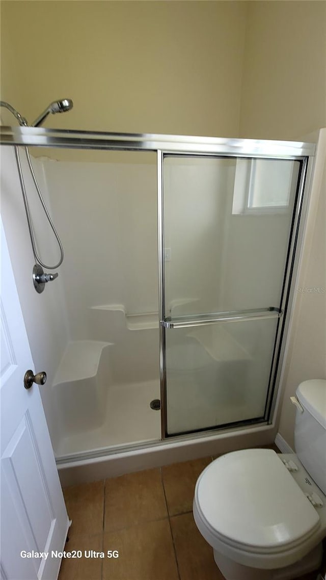 bathroom with walk in shower, toilet, and tile patterned floors