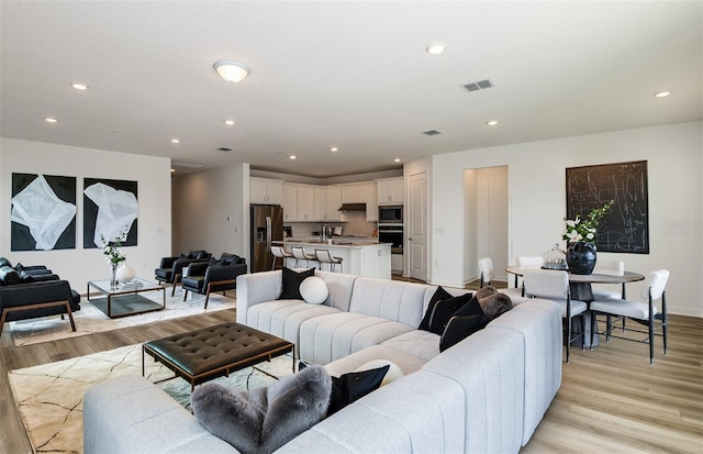 living room with recessed lighting, visible vents, and light wood-style floors