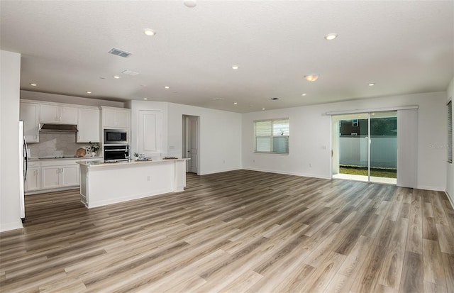 kitchen with under cabinet range hood, light wood-style flooring, appliances with stainless steel finishes, and open floor plan