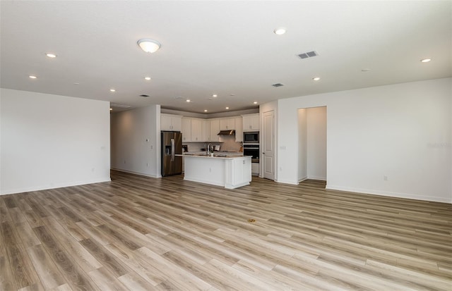 unfurnished living room with light wood-style floors, recessed lighting, visible vents, and baseboards