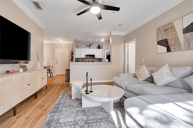 living room featuring ceiling fan, ornamental molding, and light hardwood / wood-style floors