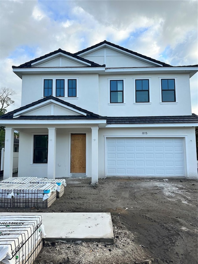 view of front of house featuring stucco siding, an attached garage, a porch, and driveway