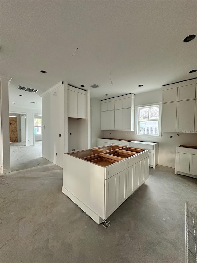 kitchen featuring plenty of natural light, concrete floors, and white cabinetry