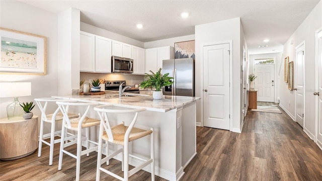 kitchen with kitchen peninsula, a breakfast bar, white cabinets, and appliances with stainless steel finishes