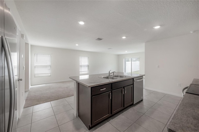 kitchen featuring dark brown cabinets, sink, an island with sink, stainless steel appliances, and light tile patterned floors