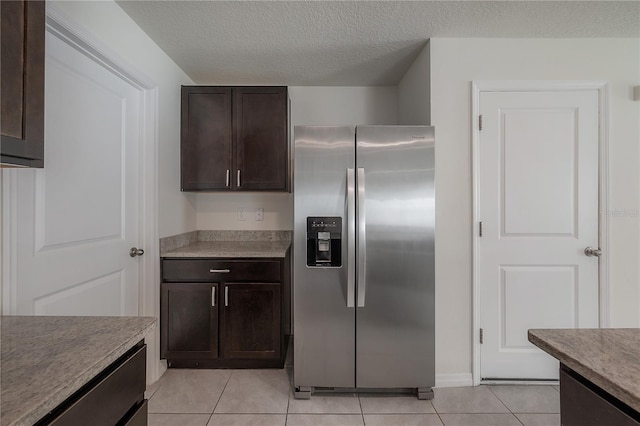 kitchen with a textured ceiling, stainless steel refrigerator with ice dispenser, dark brown cabinetry, and light tile patterned floors