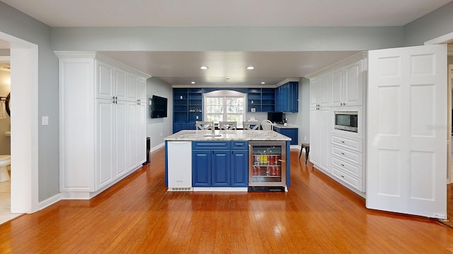 kitchen featuring blue cabinets, beverage cooler, white cabinets, and light wood-type flooring