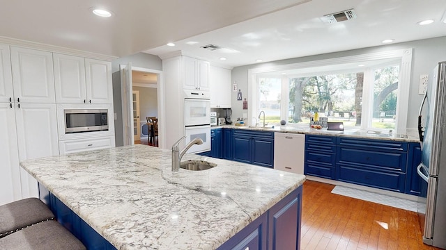 kitchen featuring blue cabinets, white cabinets, stainless steel appliances, hardwood / wood-style floors, and sink