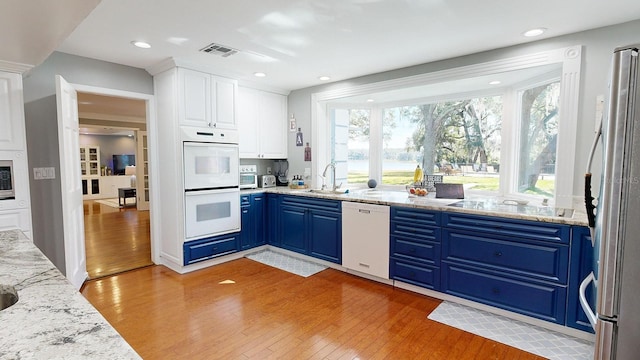 kitchen with white appliances, white cabinetry, blue cabinets, and plenty of natural light